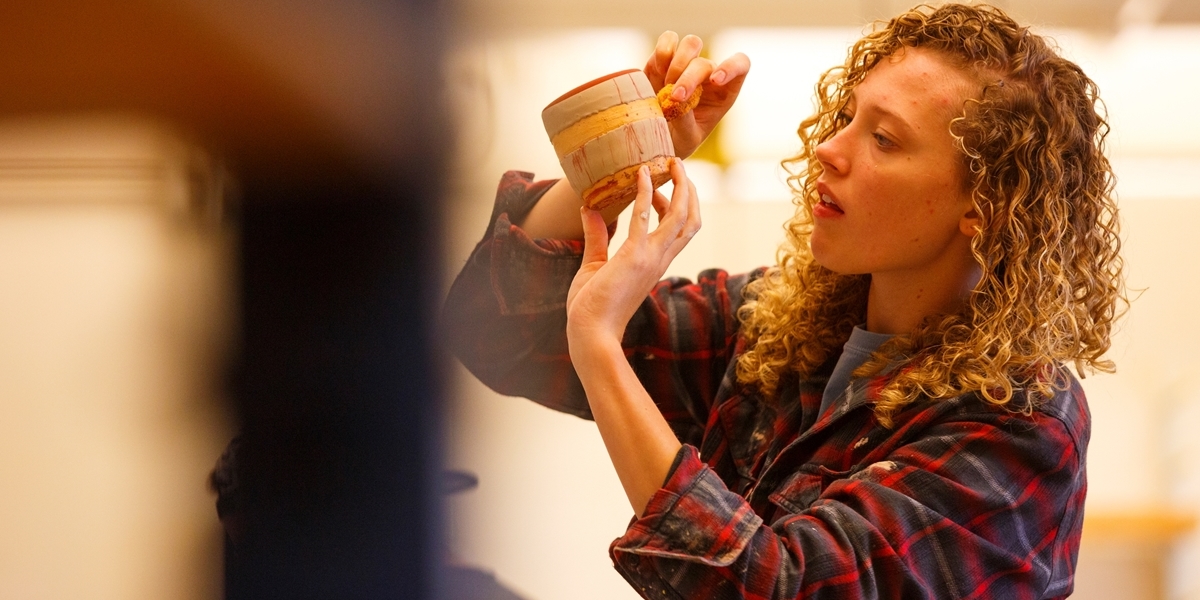 A Northwestern student touches up the glaze work on her pottery piece.
