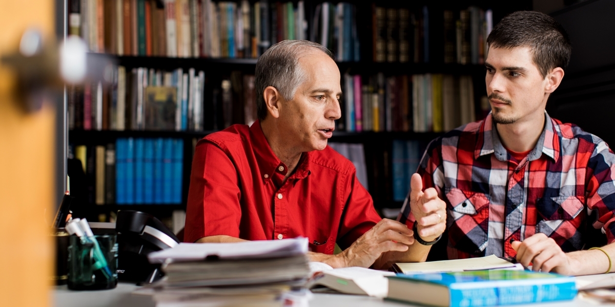 A Northwestern professor talks with a student in his office.