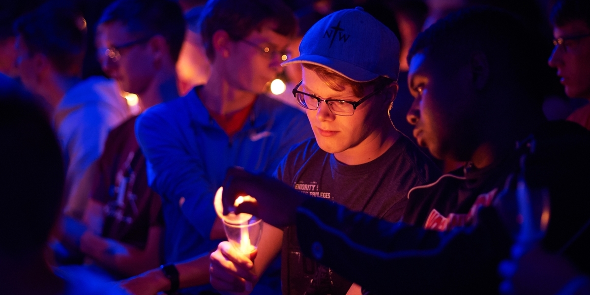 Student lighting a candle at a worship service