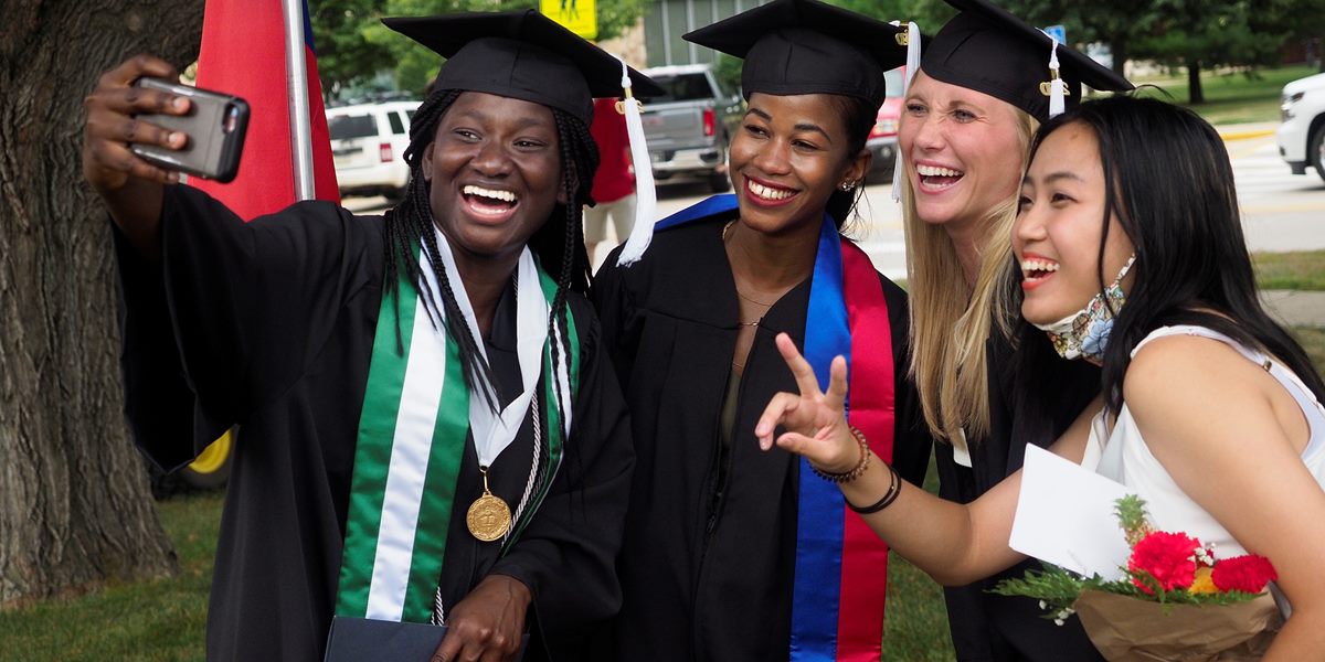 An Honors Scholar poses for a selfie with friends at commencement.